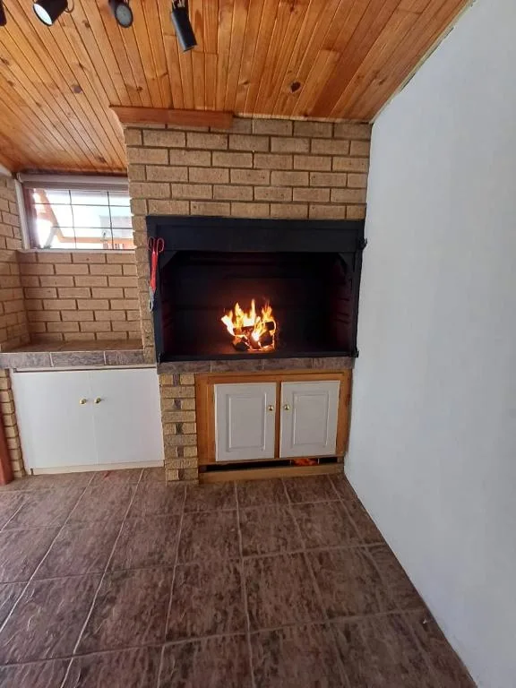 Cozy lounge area with fireplace, wooden ceiling, and brick surround