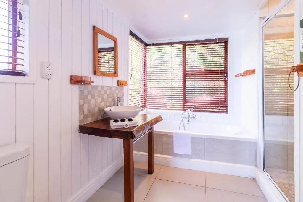 Bright bathroom with wooden vanity, bathtub, and walk-in shower enclosure