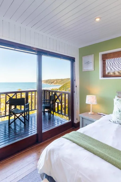 Bright bedroom with ocean view through glass doors to deck