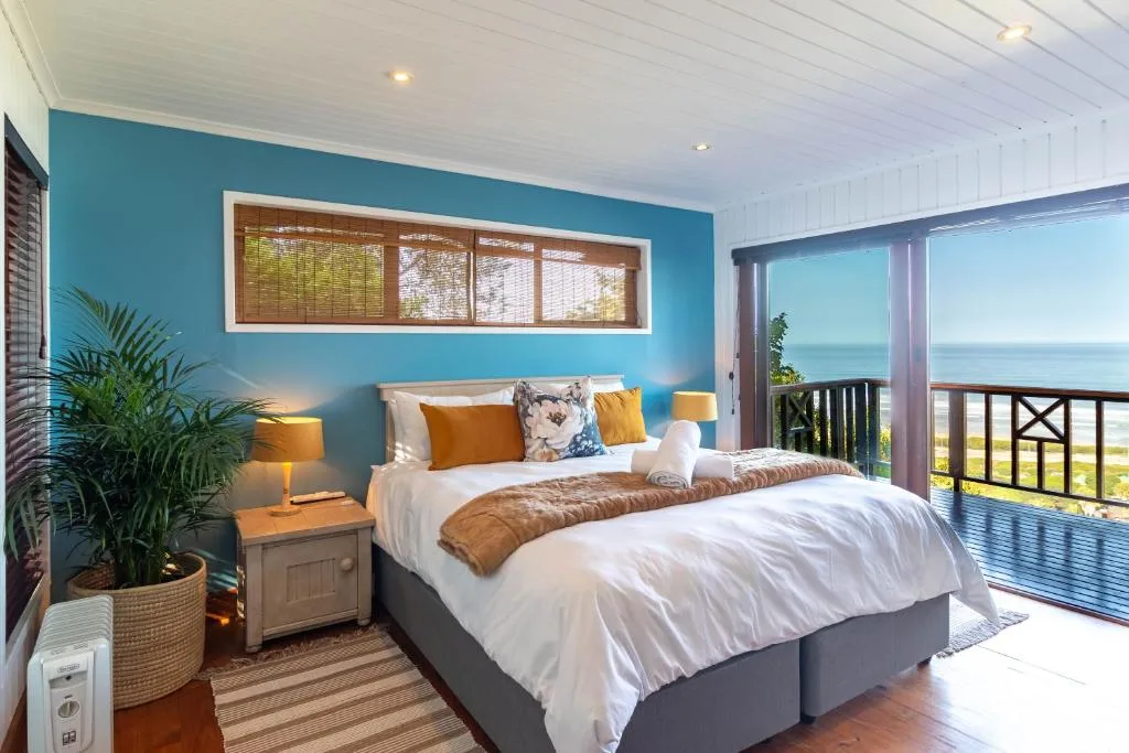 Bright bedroom with turquoise accent wall and ocean views through glass doors