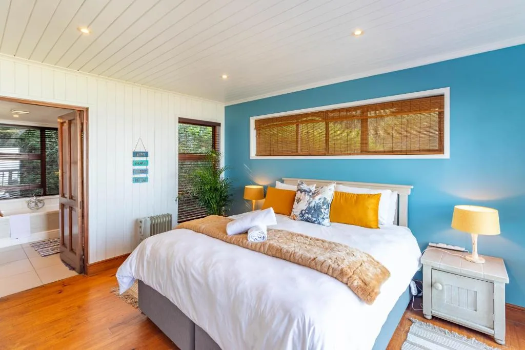 Bright bedroom with queen bed, turquoise accent wall, and wooden floors