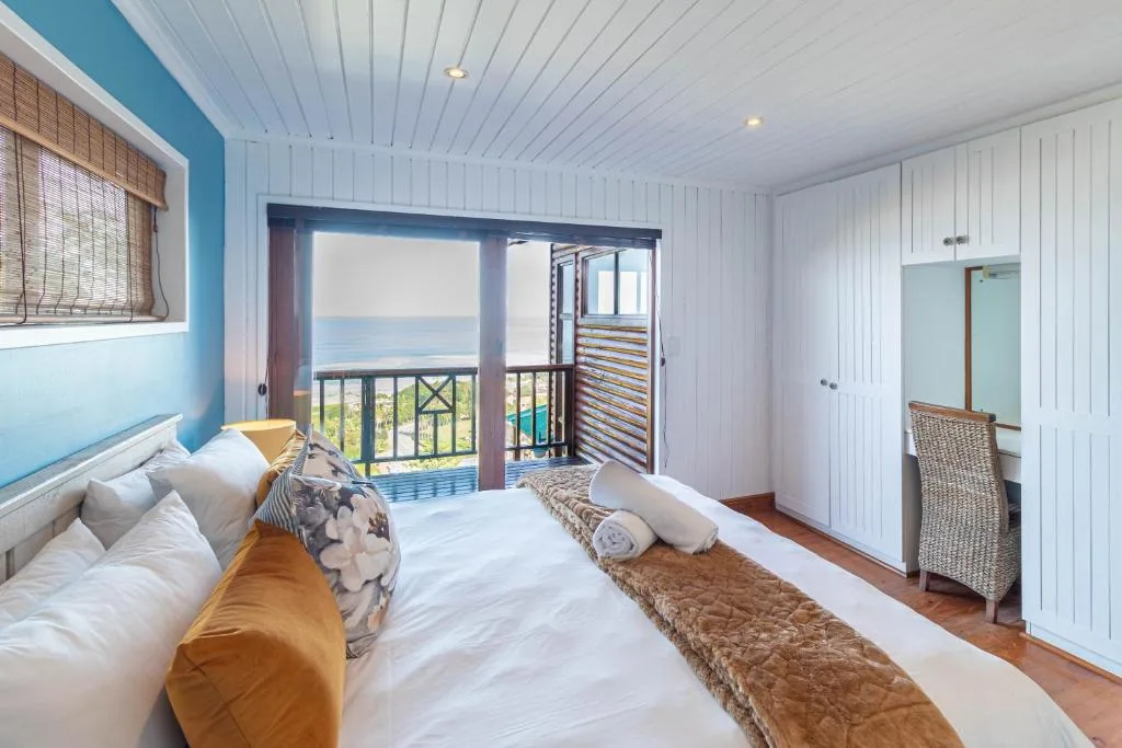 Bright bedroom with ocean view through sliding glass doors and deck access