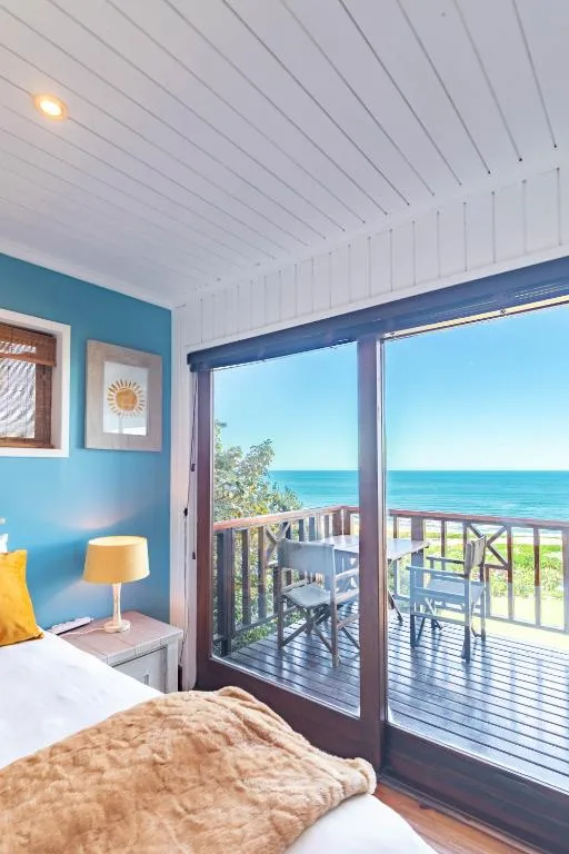 Bright bedroom with ocean view through glass doors to deck