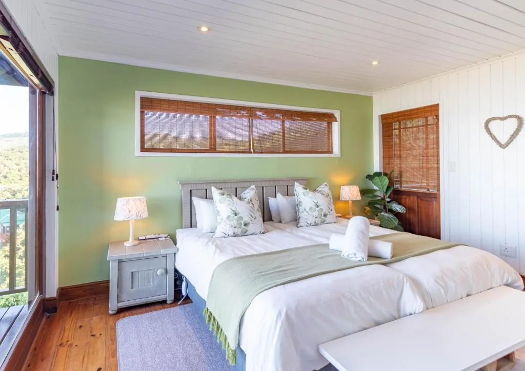 Bright bedroom with twin beds, green accent wall, and ocean view windows