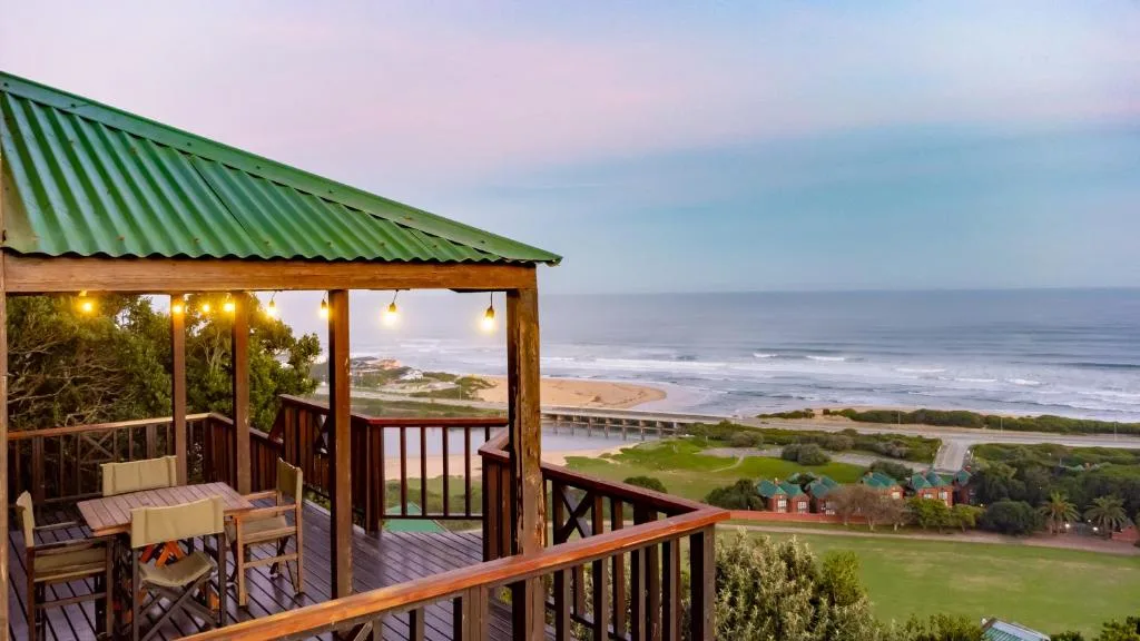 Wooden deck with seating overlooking ocean and coastline at sunset
