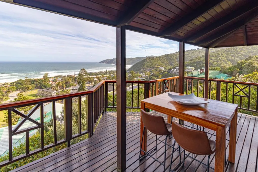 Wooden deck with dining table overlooking ocean and mountains