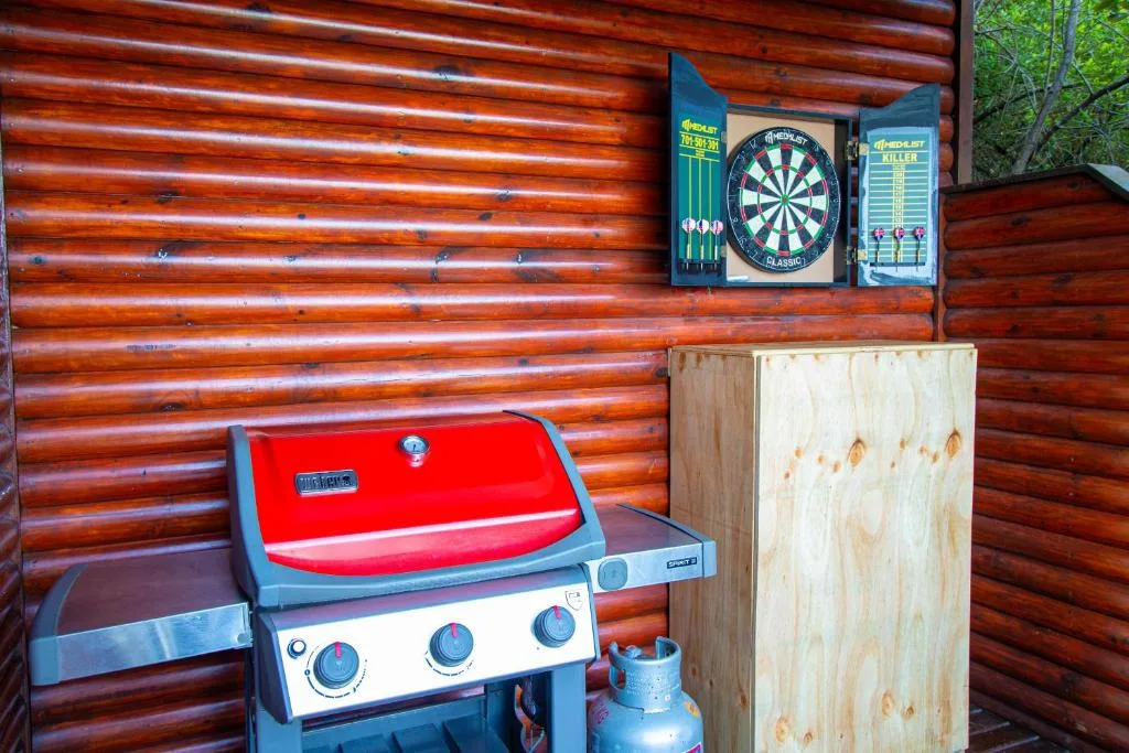 Outdoor braai area with red grill and dartboard on log cabin wall