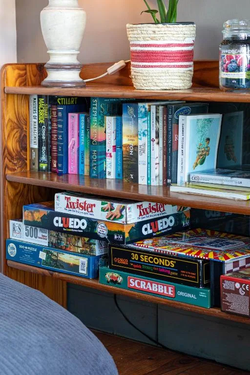 Wooden shelving unit displaying books, board games, and decorative items