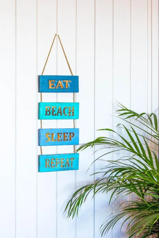 Wooden beach house sign with eat, beach, sleep, repeat text