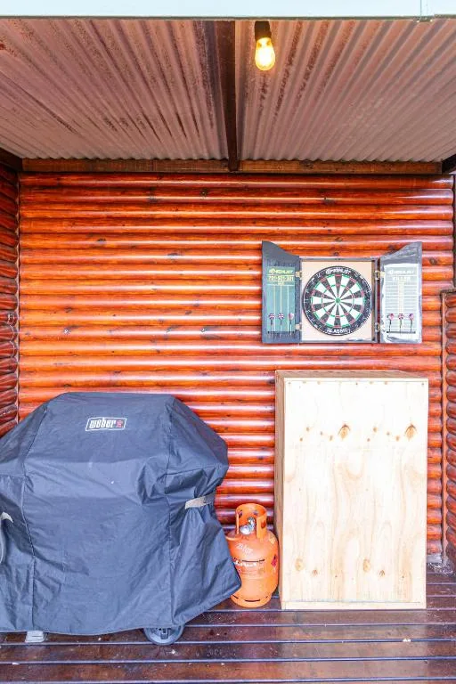 Covered outdoor braai area with dart board and BBQ grill setup