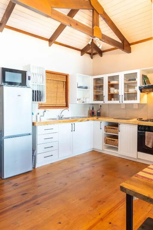 Spacious kitchen with white cabinetry, wooden counters, and vaulted ceiling beams