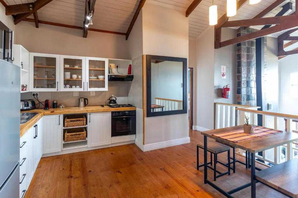 Modern kitchen with white cabinetry, wooden counters, and dining table beyond