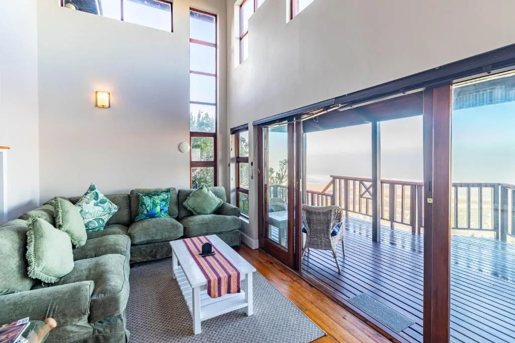 Spacious lounge with gray sofa, green cushions, and glass doors opening to deck