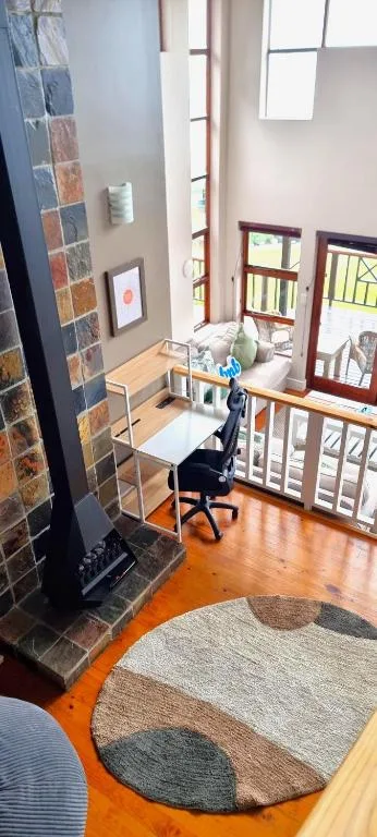 Open-plan lounge with fireplace, desk area, and large windows overlooking garden