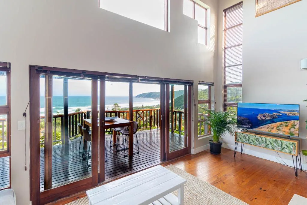 Bright lounge with ocean views through bifold doors and coastal landscape television