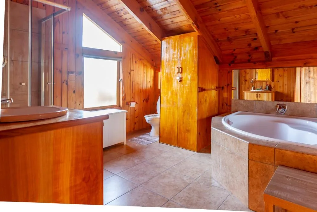 Spacious wooden bathroom with soaking tub, vanity, and shower enclosure