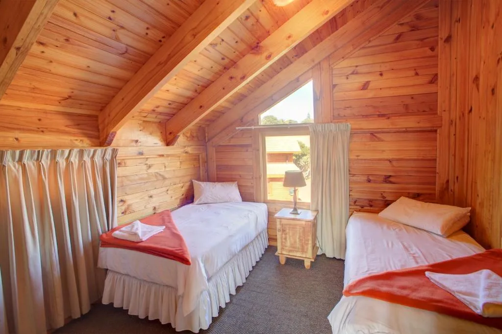 Wooden chalet bedroom with multiple beds and warm timber ceiling