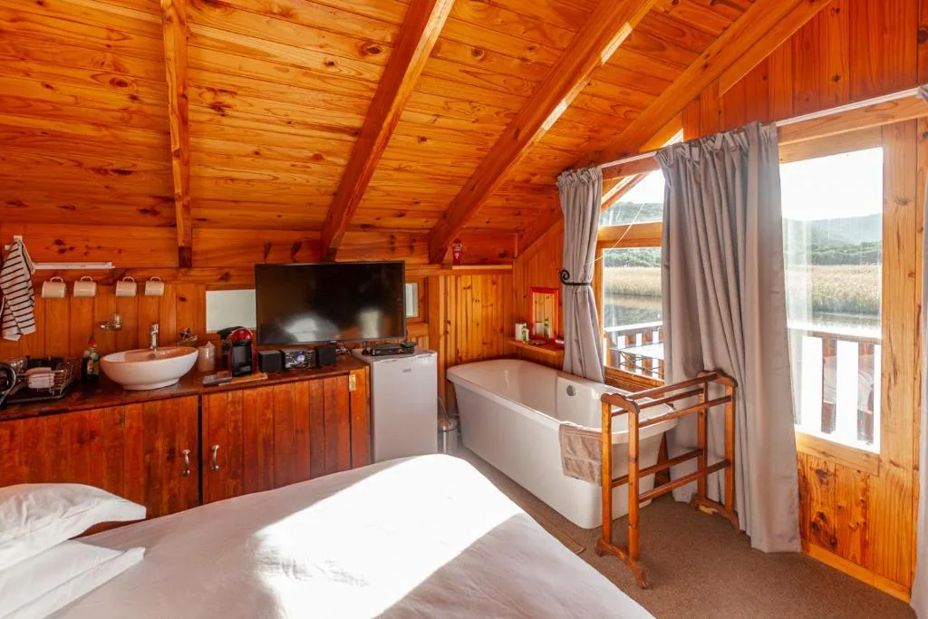 Wooden cabin bedroom with bed, bath, sink, and valley views