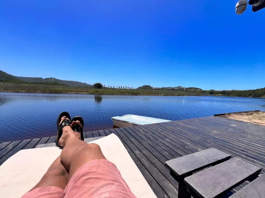 Wooden deck overlooking tranquil lagoon with loungers and scenic mountain backdrop