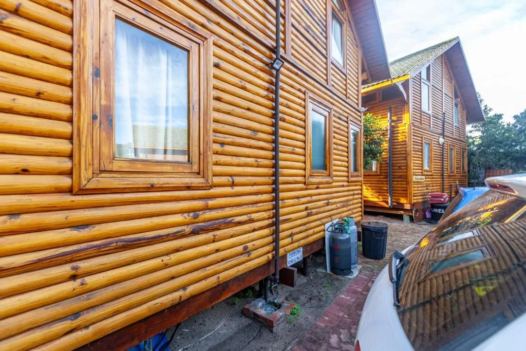 Wooden log cabin facade with large window and brick pathway