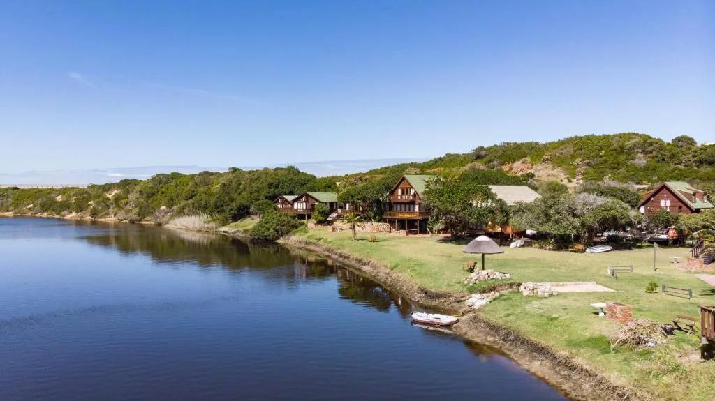 Riverside lodge with thatched roofs nestled in lush green hillside garden