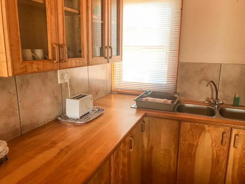 Wooden kitchen with double sink, cabinetry, and tile backsplash
