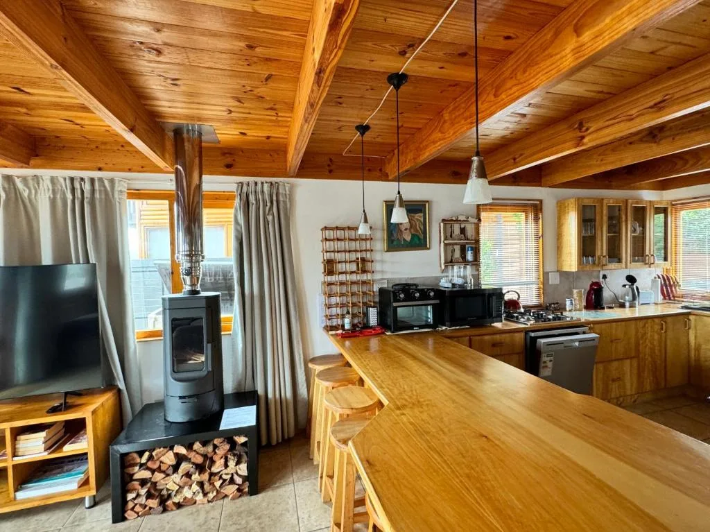 Open-plan lounge and kitchen with wooden beams and stone fireplace