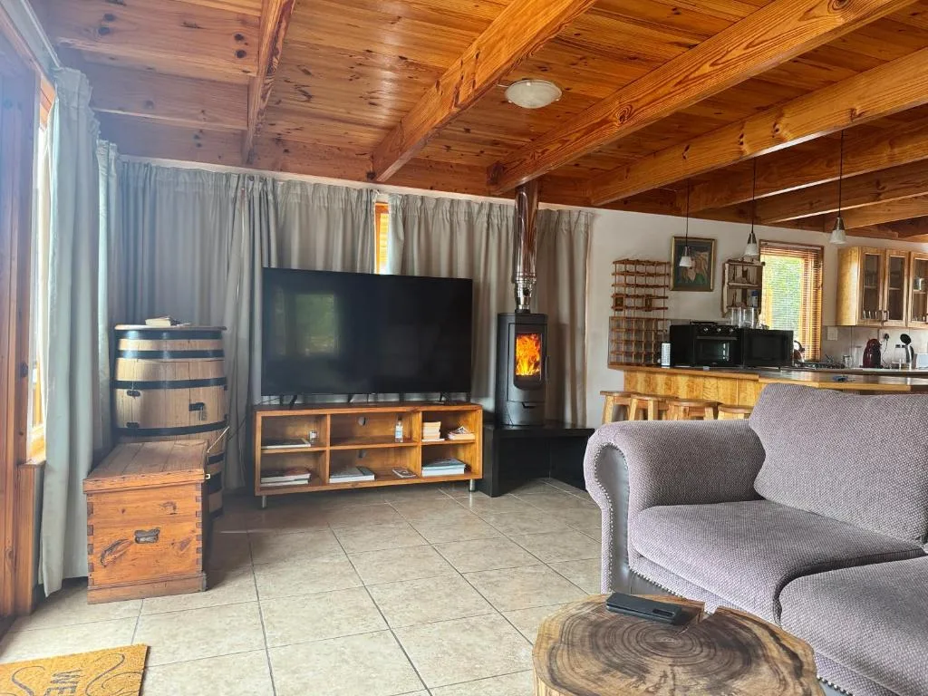 Spacious living room with sofa, large TV, fireplace, and wooden beams