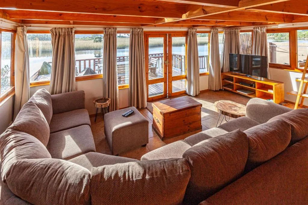 Spacious lounge with sofas overlooking lagoon through large windows and glass doors