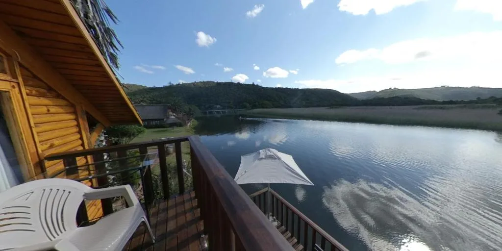 Serene lagoon view with green hills and blue sky from wooden deck