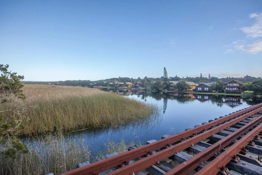 Lagoon vista with reed beds, waterfront houses, and distant hills