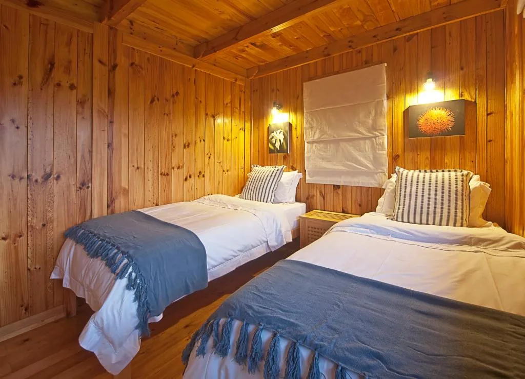 Wooden chalet bedroom with two beds and warm lighting fixtures