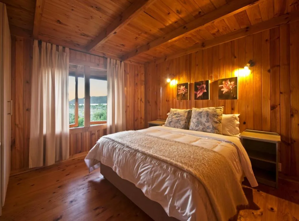 Warm wooden bedroom with queen bed and scenic garden view through windows