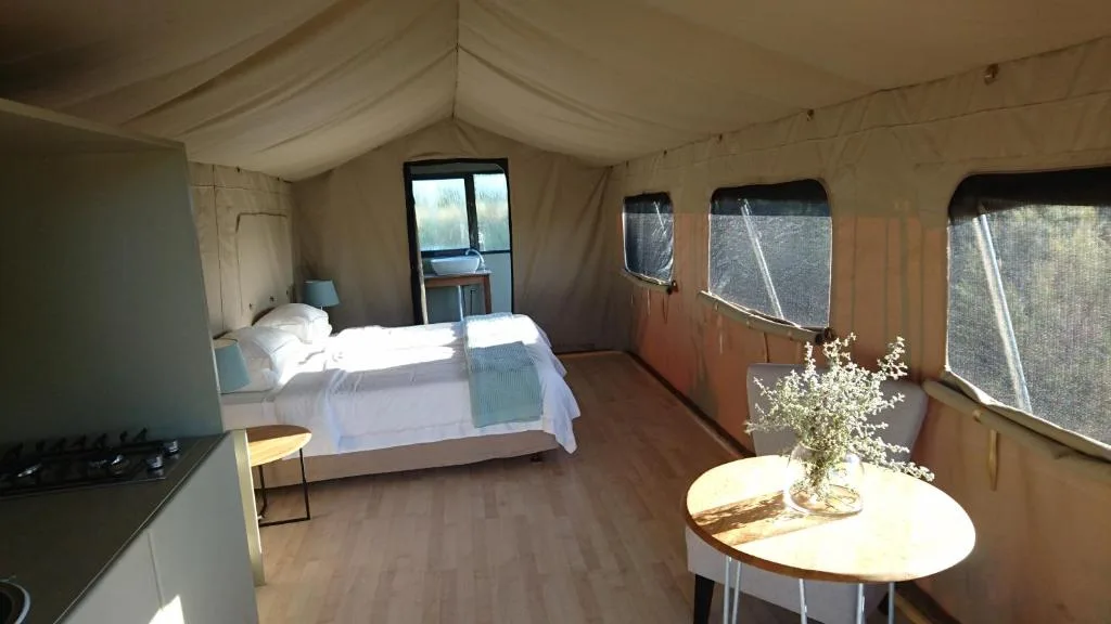 Bright canvas chalet bedroom with white bedding and round dining table