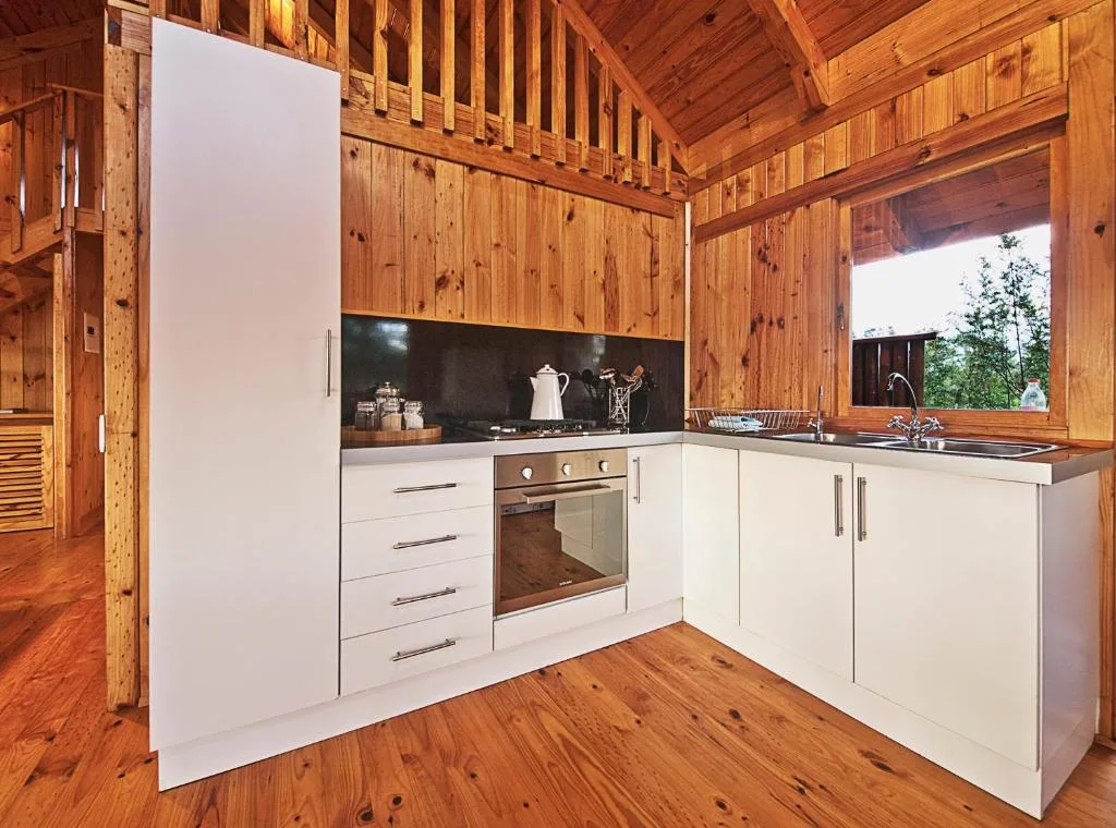 Modern white kitchen with oven, sink, and wooden cabin interior details