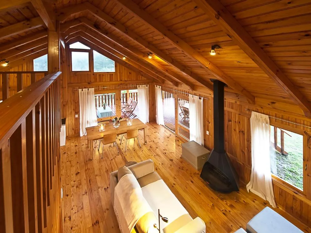 Open-plan wooden loft with sofa, dining table, and wood stove