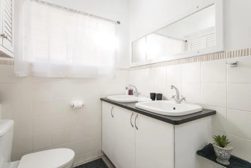 Clean bathroom with double sink vanity, toilet, and bright window