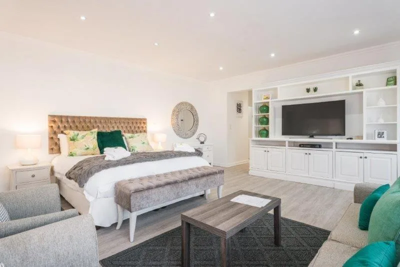Spacious master bedroom with upholstered headboard and entertainment area