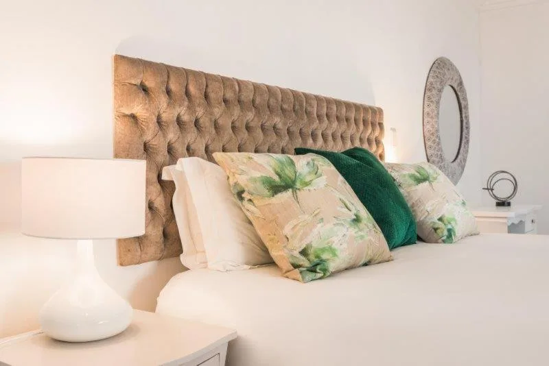 Bed with tufted headboard, patterned pillows, and bedside lamp