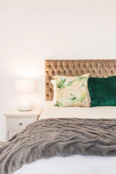 Bedroom with upholstered headboard, decorative pillows, and bedside lamp