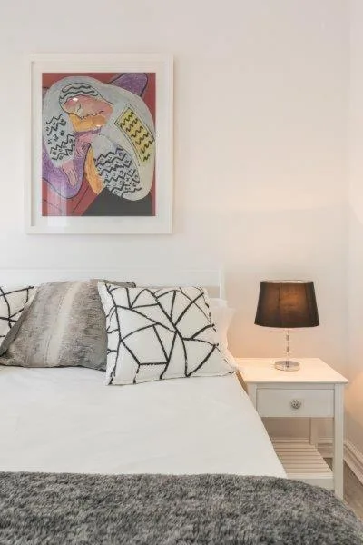 Neatly made bed with patterned pillows and bedside lamp