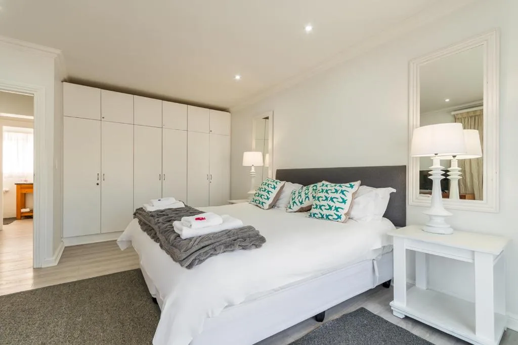 Spacious bedroom with queen bed, white wardrobe, and modern furnishings