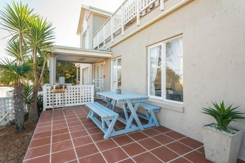 Outdoor patio with blue picnic table and palm trees, coastal setting