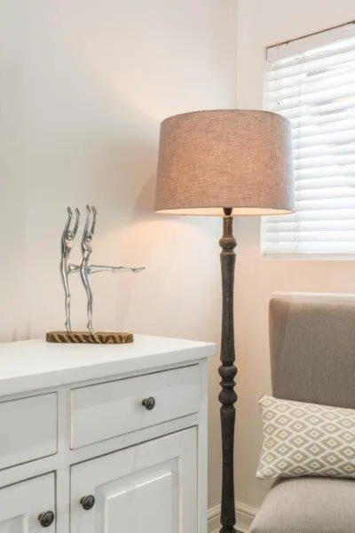 Bedroom corner with white dresser, wooden floor lamp, and decorative accessory