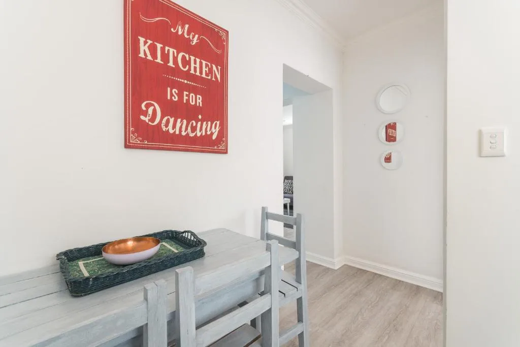 Red kitchen sign and rustic decor in bright white apartment space