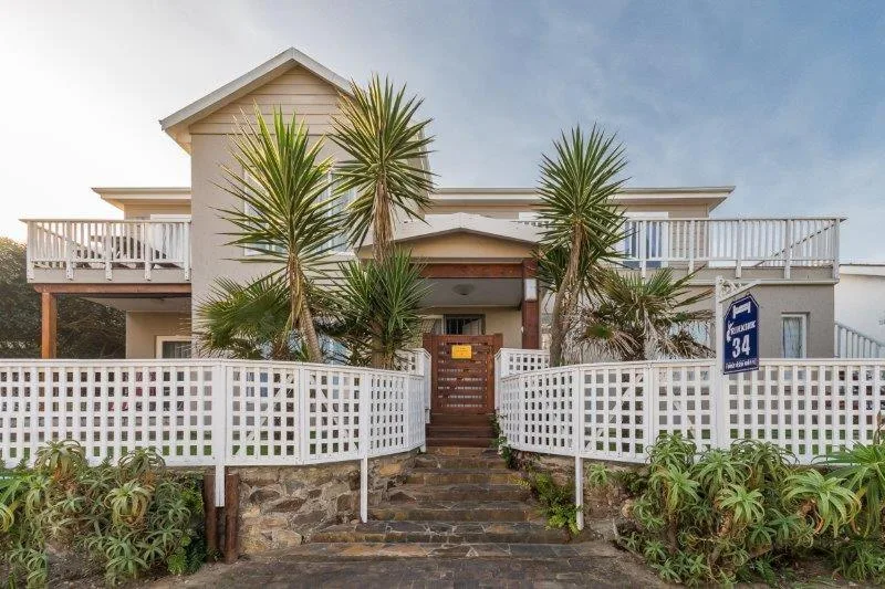 Beachfront property with white railings, palm trees, and wooden entrance gate