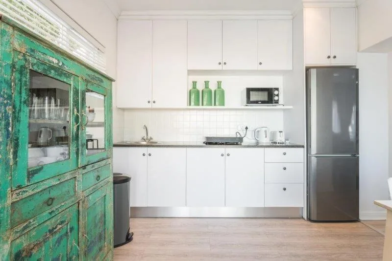 Modern kitchen with white cabinetry, black countertops, and vintage turquoise cupboard