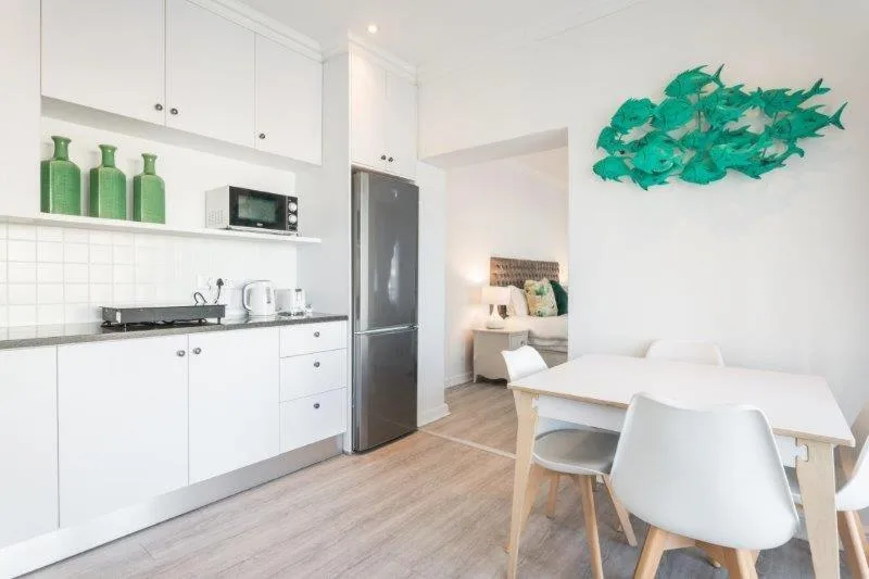Modern white kitchen with stainless steel appliances and dining area