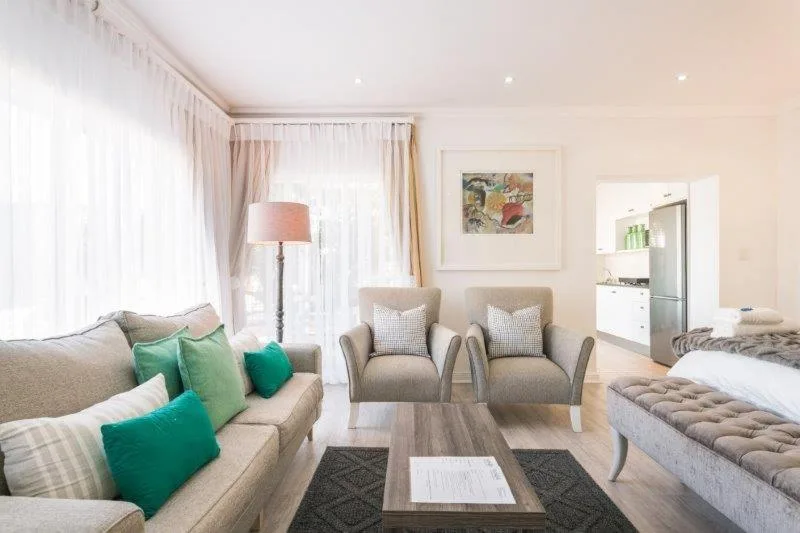 Bright lounge with beige sofas, green cushions, and armchairs around wooden table