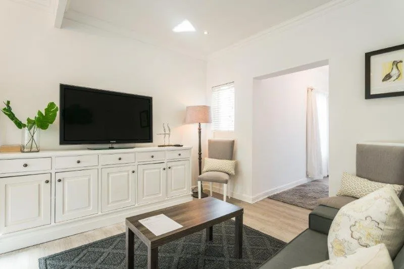 Bright lounge with TV, white cabinetry, comfortable seating, and natural light